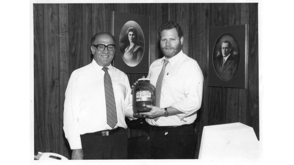 Harry (left) and Simon (right) Witenoff with framed photos of Sam and Esther Witenoff in the background.